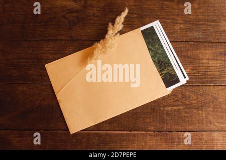 Fotos sind in einem beigen Umschlag auf einem braunen Holztisch eingeschlossen Stockfoto