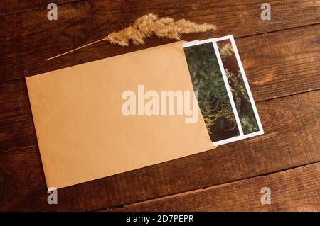 Fotos sind in einem beigen Umschlag auf einem braunen Holztisch eingeschlossen Stockfoto