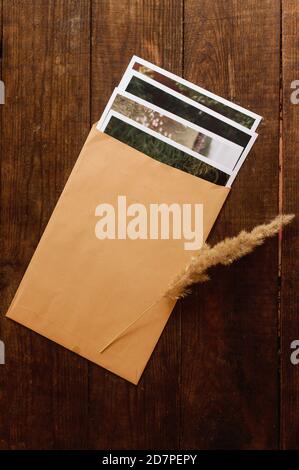 Fotos sind in einem beigen Umschlag auf einem braunen Holztisch eingeschlossen Stockfoto