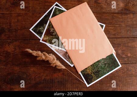 Fotos sind in einem beigen Umschlag auf einem braunen Holztisch eingeschlossen Stockfoto