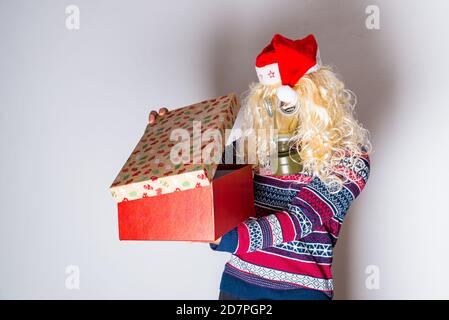 Transgender Person in weihnachtskleidung und Gesichtsschutz Blick in Die öffnende Geschenkbox Stockfoto