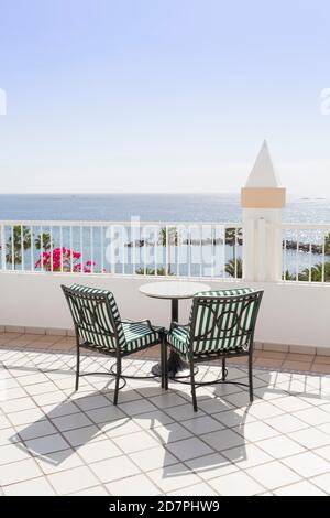 Bistrotisch und zwei leere Stühle auf einem Balkon mit Blick auf das Meer, Teneriffa, Kanarische Inseln Stockfoto