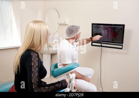 Zahnarzt, der mit dem Patienten spricht und auf einen leeren Monitor zeigt Stockfoto