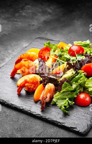 Frischer Salat mit Garnelen auf schwarzem Teller. Stockfoto