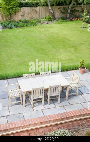 Großer Garten in Großbritannien im Sommer, mit Holzmöbeln auf einer Gartenterrasse Stockfoto