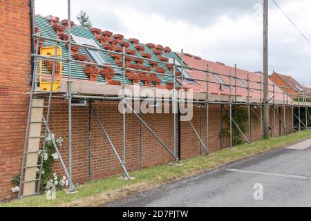 Gerüste und Dachreparaturen, die Dachziegel auf einem ländlichen Haus in Buckinghamshire, Großbritannien, ersetzen Stockfoto