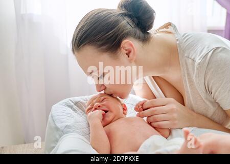 Junge Mutter küssen weinen neugeborenen Baby Sohn Stockfoto