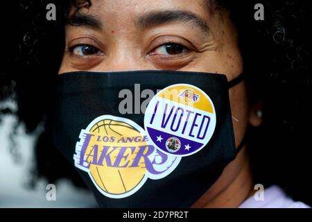 Los Angeles, Kalifornien, USA. Okt. 2020. Eine Wählerin trägt einen Sticker "Ich habe gestimmt" auf ihrer Lakers Gesichtsmaske, nachdem sie am Samstag, den 24. Oktober 2020, in einem Wahlzentrum im Staples Center in Los Angeles ihre Stimme abgegeben hat. Kredit: Ringo Chiu/ZUMA Wire/Alamy Live Nachrichten Stockfoto