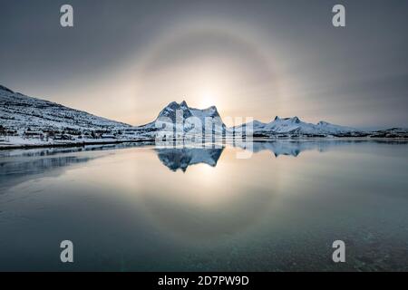 Sonnenring, Halo über schneebedeckten Bergkette Kulhornet, arktische Winterlandschaft, Kobbenestinden, vor Meer, Ballangen, Nordland, Norwegen Stockfoto