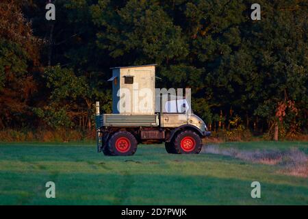 Mobiler Jagdsitz auf einem Unimog, der im Abendlicht auf einer Wiese am Waldrand steht, Schleswig-Holstein, Deutschland Stockfoto