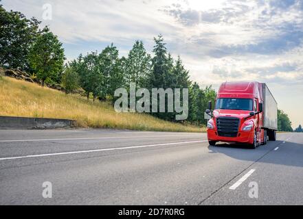 Bright Red Diesel Big Rig Industrie professionelle semi-Truck mit Schwarzer Kühlergrill, der kommerzielle Ladung in einem trockenen Transporter transportiert Fahren auf der St. Stockfoto