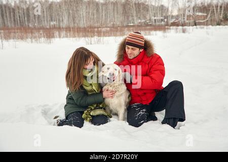 Porträt eines jungen Paares mit Hund auf einem Winterspaziergang. Mann und Frau mit labrador Stockfoto