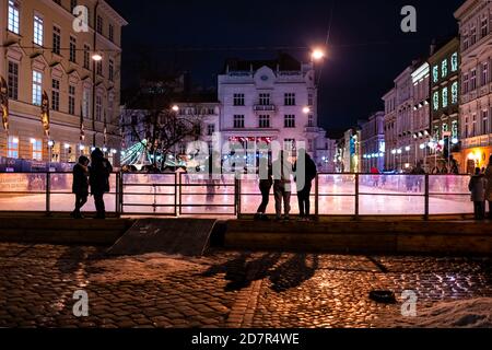 Lviv, Ukraine - 27. Dezember 2019: Marktplatz der Altstadt mit Nachteisbahn in Lvov und Weihnachtsbeleuchtung Lichter, Menschen Schlittschuh Stockfoto