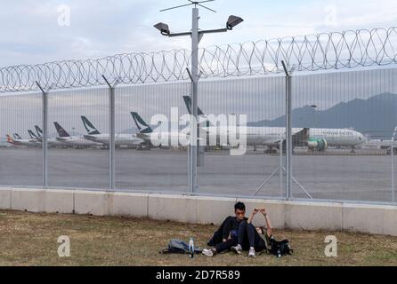 Ein Paar, das sich als Flugzeug der Hongkonger Fluggesellschaft Cathay Pacific Airways auf der Landebahn des Hong Kong International Airport auf dem Rasen niedergelassen hat.Cathay Pacific eine Hongkonger Airline-Gruppe hat eine Unternehmensumstrukturierung als Reaktion auf die Wirtschaftskrise COVID-19 angekündigt, die 8,500 Arbeitsplätze verringern wird Und schloss seine regionale Fluggesellschaft Cathay Dragon. Stockfoto