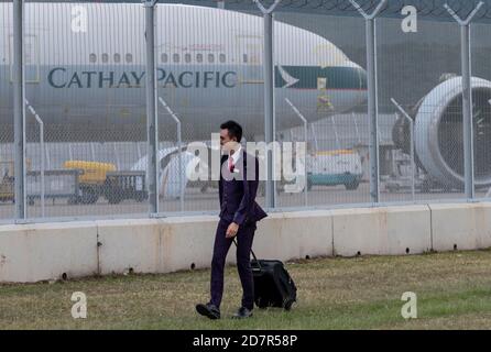 Ein Flugbegleiter von Hong Kong Airlines, der als Flugzeug der Hong Kong Airline Cathay Pacific Airways durch das Gras läuft, ist auf der Start- und Landebahn des Hong Kong International Airport stationiert.Cathay Pacific eine Airline-Gruppe von Hong Kong hat eine Unternehmensumstrukturierung als Reaktion auf die Wirtschaftskrise COVID-19 angekündigt Wird 8,500 Arbeitsplätze zu kürzen und seine regionale Fluggesellschaft Cathay Dragon zu schließen. Stockfoto