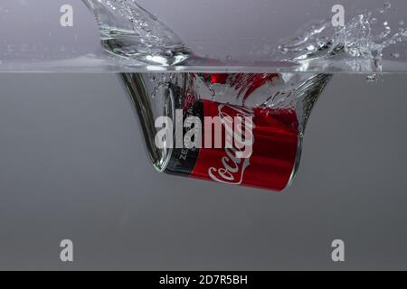 Nahaufnahme der Coca Cola, die auf grauem Hintergrund ins Wasser fällt. Wunderschöne Hintergründe. Stockfoto