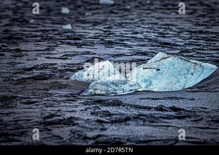 Nahaufnahme abstrakte Ansicht des kaltblauen Gletschereisbergs in Jokulsarlon Lagune See Diamant Strand in Island mit schwarzem Sand auf Ufer Stockfoto