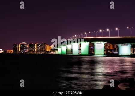 John Ringling Causeway Brücke in Sarasota Bay Florida bei dunkler Nacht mit Stadtlichtern, Wolkenkratzern Gebäude Stadtbild Skyline im Hintergrund und Wasser Stockfoto