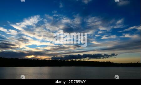 Toller Sonnenuntergang über dem Wasser. Schöne Landschaft mit einem See und dramatischen Himmel mit Cumulus Wolken am Horizont. Stockfoto