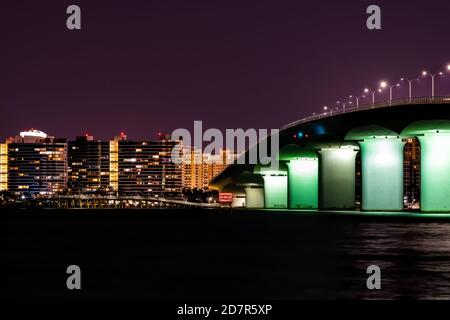 John Ringling Causeway Brücke beleuchtet in Sarasota Bay Florida in dunkler Nacht mit Stadtlichtern, Wolkenkratzer Gebäude Stadtbild Skyline in Backgroun Stockfoto