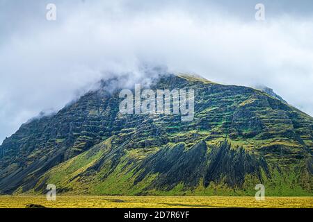 Island Berglandschaft Blick auf die Klippe an bewölkten Tag auf südliche Ringstraße mit Nebelnebel im Sommer in der Nähe Fjadrargljufur Stockfoto