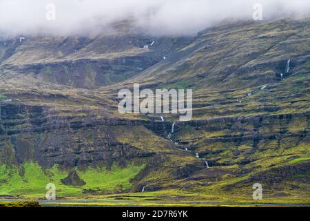 Island Berglandschaft Blick auf Klippe und Wasserfall Fluss auf wolkiger Tag auf südlicher Ringstraße im Sommer in der Nähe Fjadrargljufur Stockfoto