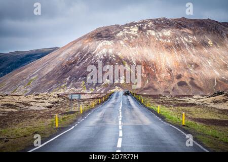 Lavafeld auf der Halbinsel Snaefellsnes in Island mit niemand auf Blick auf die Straße geradeaus und felsige Klippe wolkiger Tag Stockfoto