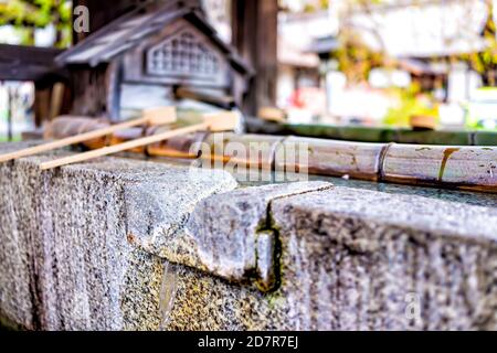 Reinigungswasserbrunnen in der Nähe in Kyoto, Japan mit Bambuspfannen und Bach, der aus dem Auslauf fließt Stockfoto