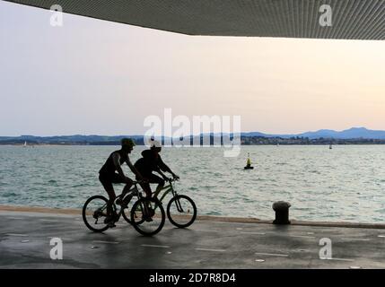 Radfahrer fahren entlang der Paseo Maritimo de Santander Kantabrien Spanien An einem sonnigen Oktobermorgen im Schatten der Centro Botin Kunstzentrum Stockfoto