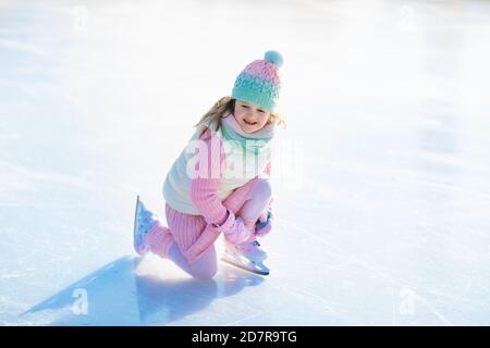 Kind Schlittschuhlaufen auf Natureis auf sonnigen Wintertag. Kinder mit Schlittschuhen. Kleines Mädchen Schlittschuhlaufen auf zugefrorenen See in Snowy Park. Schnee und Winter Spaß. Gesunde heraus Stockfoto