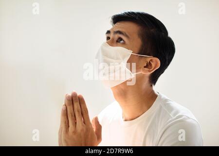 Betet für das Opfer des Coronavirus. Asiatischer Mann im Gesicht Maske beten für krank. Patient in Krankenhauskapelle oder Kirche während Covid-19 Ausbruch. Viruspandemie. P Stockfoto