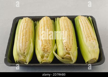 Cobs von süßen rohen Mais in Kunststoff-Behälter schließen Stockfoto