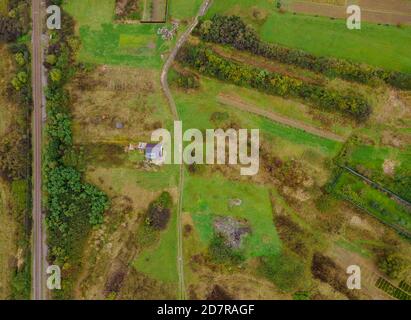 Blick von oben oder Luftaufnahme von frischen grünen Feldern und Dorf Blick vor der Ernte im Sommer Stockfoto