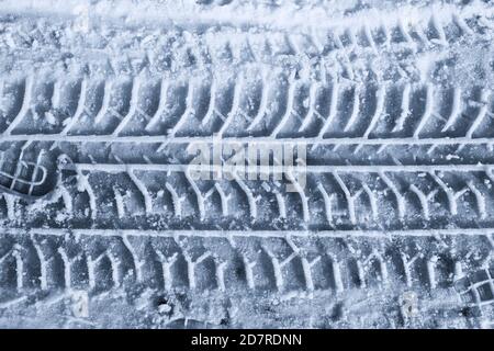 Spur von Protector Autoreifen im geschmolzenen Schnee. Draufsicht in blauer Tonung. Nahaufnahme. Stockfoto