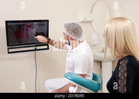 Zahnarzt, der mit dem Patienten spricht und auf einen leeren Monitor zeigt Stockfoto