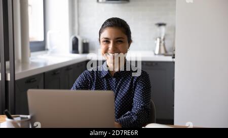 Porträt einer lächelnden indischen Frau, die auf dem Laptop arbeitet Stockfoto