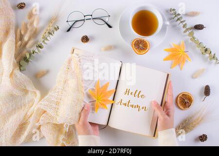 Herbstkonzept. Frau öffnete Buch auf dem Tisch mit Text Hallo Herbst. Stockfoto