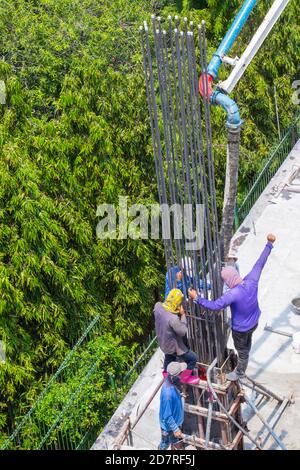 Arbeiter Gießen von Zement in Fundamente und Säulen Schalung auf der Baustelle. Stockfoto