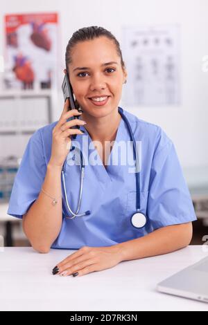 Medizinisches Personal, das mit dem Patienten telefoniert, über die Diagnose lächelt an der Kamera. Krankenschwester, Arzt mit einem Telefongespräch mit kranken Person während der Konsultation, Medizin. Stockfoto