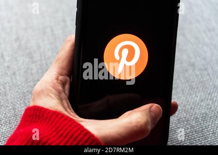 Junge Frau hält ein Smartphone mit Pinterest App auf dem Bildschirm. IPhone 11 mit einem Social-Media-App-Logo für interessante und außergewöhnliche Inhalte. Stockfoto