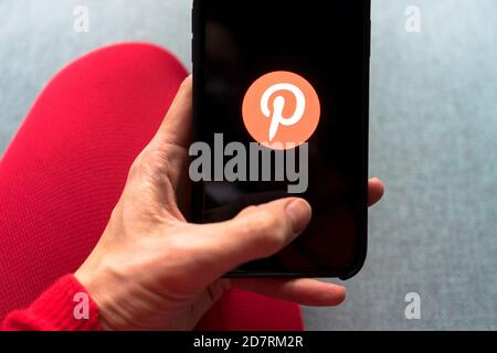 Junge Frau hält ein Smartphone mit Pinterest App auf dem Bildschirm. IPhone 11 mit einem Social-Media-App-Logo für interessante und außergewöhnliche Inhalte. Stockfoto