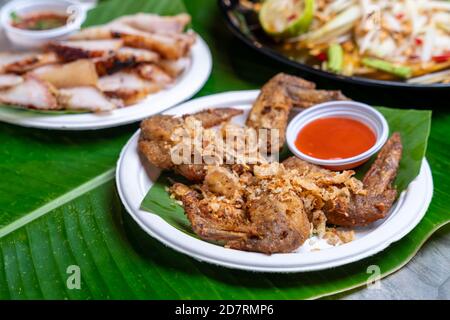 Street Food in thailand Öl gebratenen Chicken Wings. Serviert mit Tomate auf Bananenblatt Stockfoto