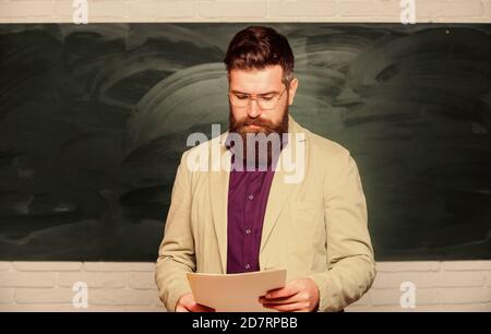 Theorie erklären. College und High School. Vorbereitung auf den Test. Lehrer bärtiger Mann hält Dokumente Hintergrund des Schwarzen Bretts. Unterlagen für Lehrer. Schulleiter. Anspruchsvoller Lehrer. Dozent im Klassenzimmer. Stockfoto