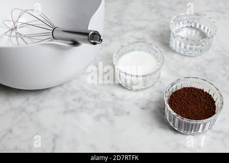 Dalgona Kaffeezutaten auf einem Marmortisch: Instant-Kaffee, Zucker und Wasser Stockfoto