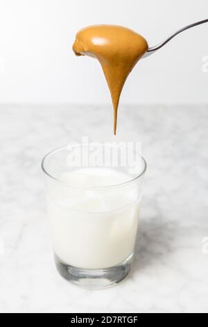 Schlagsahne in ein Glas mit Milch und Eiswürfeln gießen. Dalgona Kaffeezubereitung Stockfoto