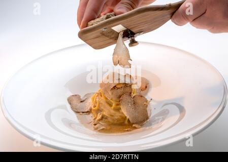 Servieren Sie den weißen Trüffel aus Alba in Italien mit einem Slicer auf einem Teller Tagliolini-Spaghetti mit Ei Stockfoto