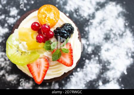 Schokoladen-Mini-Kuchen mit Frischkäse, Obst und Beeren. Draufsicht, Kopierbereich. Nahaufnahme, geringe Schärfentiefe Stockfoto