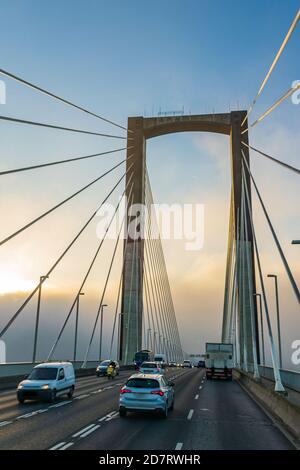 Fahrzeuge fahren über eine Brücke mit Nebelschwaden im Hintergrund. Stockfoto