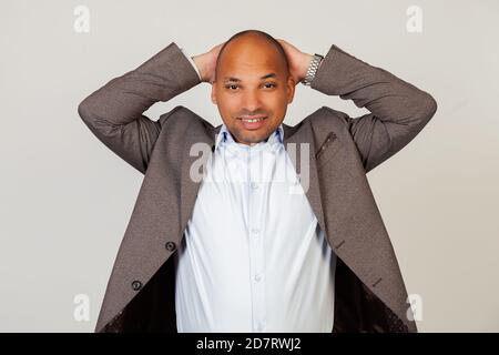 Porträt eines verärgerten jungen afroamerikanischen Mannes Geschäftsmann Blick auf die Kamera hält die Hände in seinem Kopf. Stehen auf einem grauen Hintergrund Stockfoto