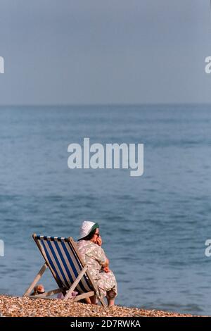 Urlauber und Touristen mit Liegestühlen am Kiesstrand in der Nähe des Palace Pier in Brighton. 20. Juli 1995. Foto: Neil Turner Stockfoto